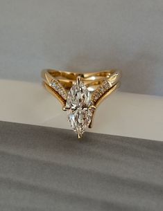 a gold ring with a pear shaped diamond in the center and side stones on each band