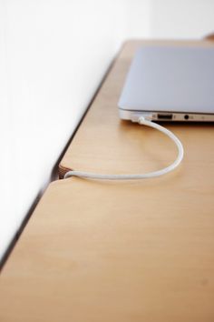 an open laptop computer sitting on top of a wooden desk next to a white wall