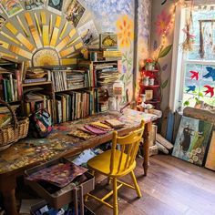 a room filled with lots of books on top of a wooden table next to a window