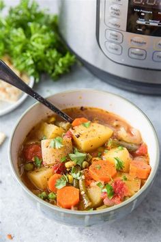 a white bowl filled with vegetable soup next to an instant pot