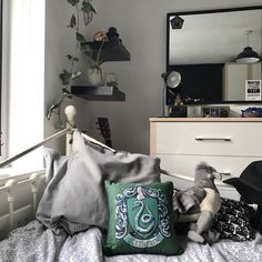 a stuffed animal sitting on top of a bed next to a mirror and dresser in a bedroom