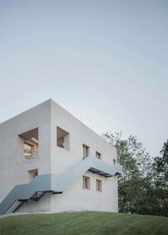 a white building with stairs leading up to the second floor and windows on top of it