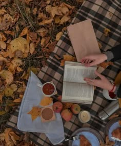 two people sitting on the ground with food and an open book in front of them