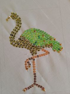 a beaded flamingo is sitting on top of a piece of cloth with beads