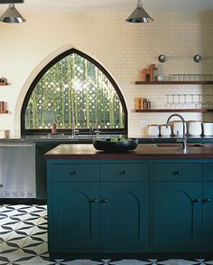 a kitchen with black and white tile flooring next to an arched window in the wall