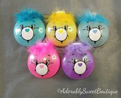 five brightly colored balls with faces painted on them are sitting in a row and one has blue, yellow, pink, and purple hair