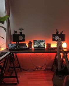 there is a desk with musical instruments on it and a keyboard in front of the monitor