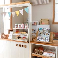 a small bakery with lots of food on the counter and bunting flags hanging from the ceiling