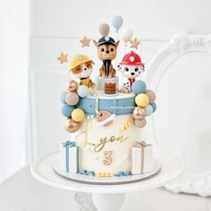 a birthday cake decorated with figurines and balloons