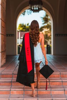 a woman wearing a graduation gown and holding a black bookbag walking down the stairs