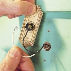 a person is plugging wires into a wall outlet with a light switch in the background