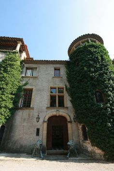 an old building with ivy growing on it's side and two statues in front