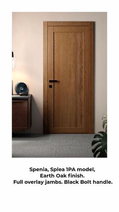 a wooden door sitting next to a plant on top of a table in front of a white wall