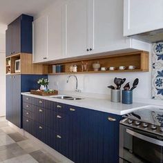 a kitchen with blue and white cabinets, an oven, sink and stove in it