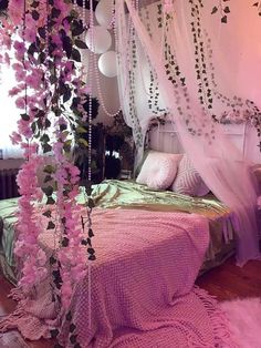 a bed covered in pink flowers next to a white canopy over it's headboard