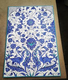 a large blue and white tile with birds on it's side, sitting on the ground