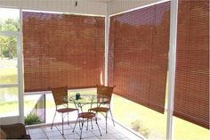 an enclosed patio area with table and chairs next to sliding glass doors that have brown blinds on them