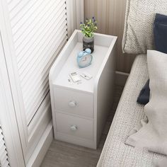 a small white nightstand next to a bed