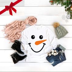 a snowman t - shirt, scarf and booties are laid out on the floor