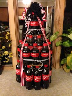 a christmas tree made out of coca - cola bottles with ribbons and bows on it