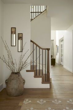 a vase with some flowers in it sitting on the floor next to a stair case