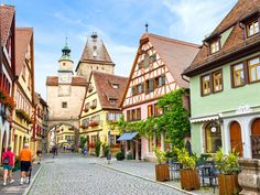 people walking down a cobblestone street in an old european town with tall buildings