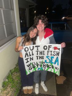 two people holding up a sign that says out of all the fish in the sea