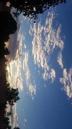 the sun shines through clouds in the sky above some buildings and trees on a sunny day