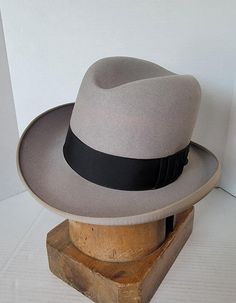 Here, for your consideration, is this beautiful stunning Gray homberg hat, with a nice curled brim and grograin edge. Comes with a contrasting black ribbon with a pleated bow, just  gorgeous. Please view pictures as they are part of the description.  Measurements are approximate: Brim measures 2 1/2 inches, and Crown measures 5 1/2 inches.  Marked Size 7 1/8 Label reads: K.A. Lundstorm Hats, San Francisco's Leading Hatter, 754 Market St., Blended Hares. Please view photos as they are part of the description.  Condition: With the exception of a few small light spots and sweatband detached in one area this grey homberg appears in great condition. Please view photos as they are part of the description.  HAT BLOCK/MANNEQUIN NOT INCLUDED Computers show color differently, so please keep that in Classic Gray Hat Bands With Flat Brim, Classic Gray Flat Brim Hat Band, Classic Gray Flat Brim Hat, Classic Gray Brimmed Hat, Classic Gray Hat With Short Brim, Classic Gray Wide Brim Fedora, Classic Gray Fedora With Curved Brim, Kentucky Derby Top Hat With Flat Bill, Vintage Fedora For Kentucky Derby With Flat Bill