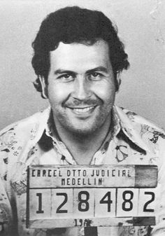 an old photo of a man smiling and holding a license plate in front of him