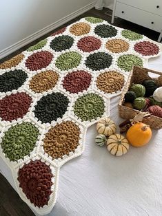 a crocheted blanket on a bed with pumpkins and gourds next to it