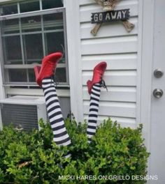 someone wearing striped socks and red shoes standing in front of a house with their feet up