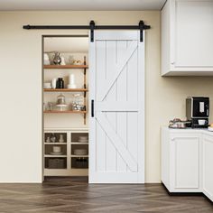 an open sliding barn door in a kitchen with white cabinets and wood flooring on the walls