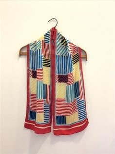 A vintage 1970s silk scarf. The long scarf is in a graphic striped basket weave design in red, yellow, black and aqua blue with a narrow red stripe outlining the center pattern.  The scarf has a machine stitched hem. Fair vintage condition with pinholes Measures 52”l x 10”w Retro Silk Scarf, Sailor Pants, Silky Blouse, Gathered Skirt, Embroidered Pillow, Red Stripe, Basket Weave, Long Scarf, Vintage 1970s