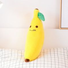 a stuffed banana sitting on top of a bed next to a framed picture hanging above it