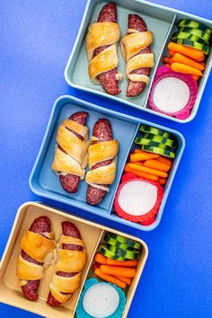 two trays filled with sandwiches and veggies on top of a blue table