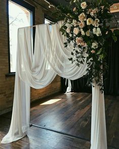 an arrangement of flowers and greenery decorates the top of a wedding ceremony arch