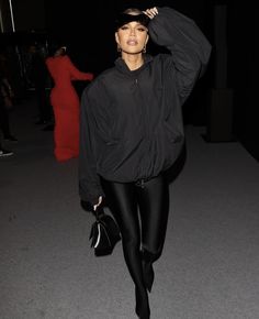 a woman in black is posing for the camera with her hand on her head and wearing leggings