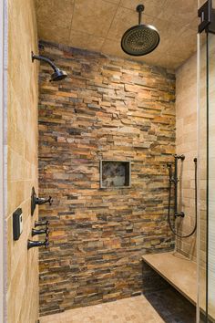 a walk in shower sitting next to a wooden bench under a faucet mounted on a wall