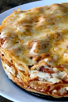 a pizza covered in cheese and sauce on a white plate with a wooden table behind it