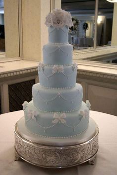 a large blue wedding cake sitting on top of a white tablecloth covered round plate