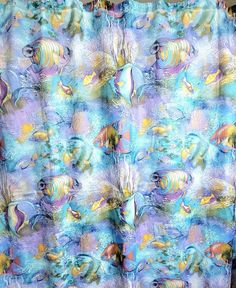 a shower curtain with fish on it in blue and purple colors, hanging from a bathroom wall