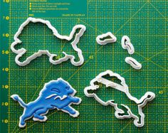 three cookie cutters shaped like animals on a green cutting board with scissors and paper