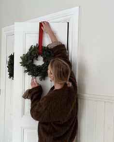 a woman is hanging a wreath on the door