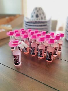 a table topped with lots of bottles filled with pink liquid next to stacks of plates