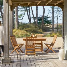 a woman standing on a porch next to a table and chairs