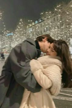 a man and woman kissing in front of christmas lights