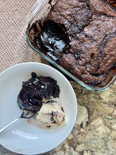 a bowl of ice cream next to a brownie in a glass dish on a table