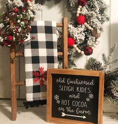 a chalkboard sign sitting in front of a christmas wreath and other holiday decorations on display