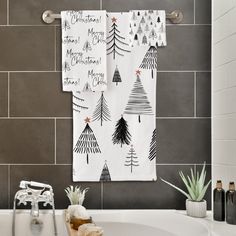 two christmas trees are hanging on the towel rack above a bathtub in a bathroom